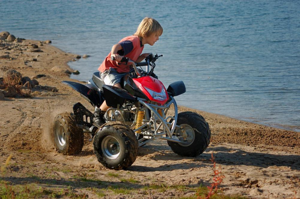 A young boy on an ATV at the beach.