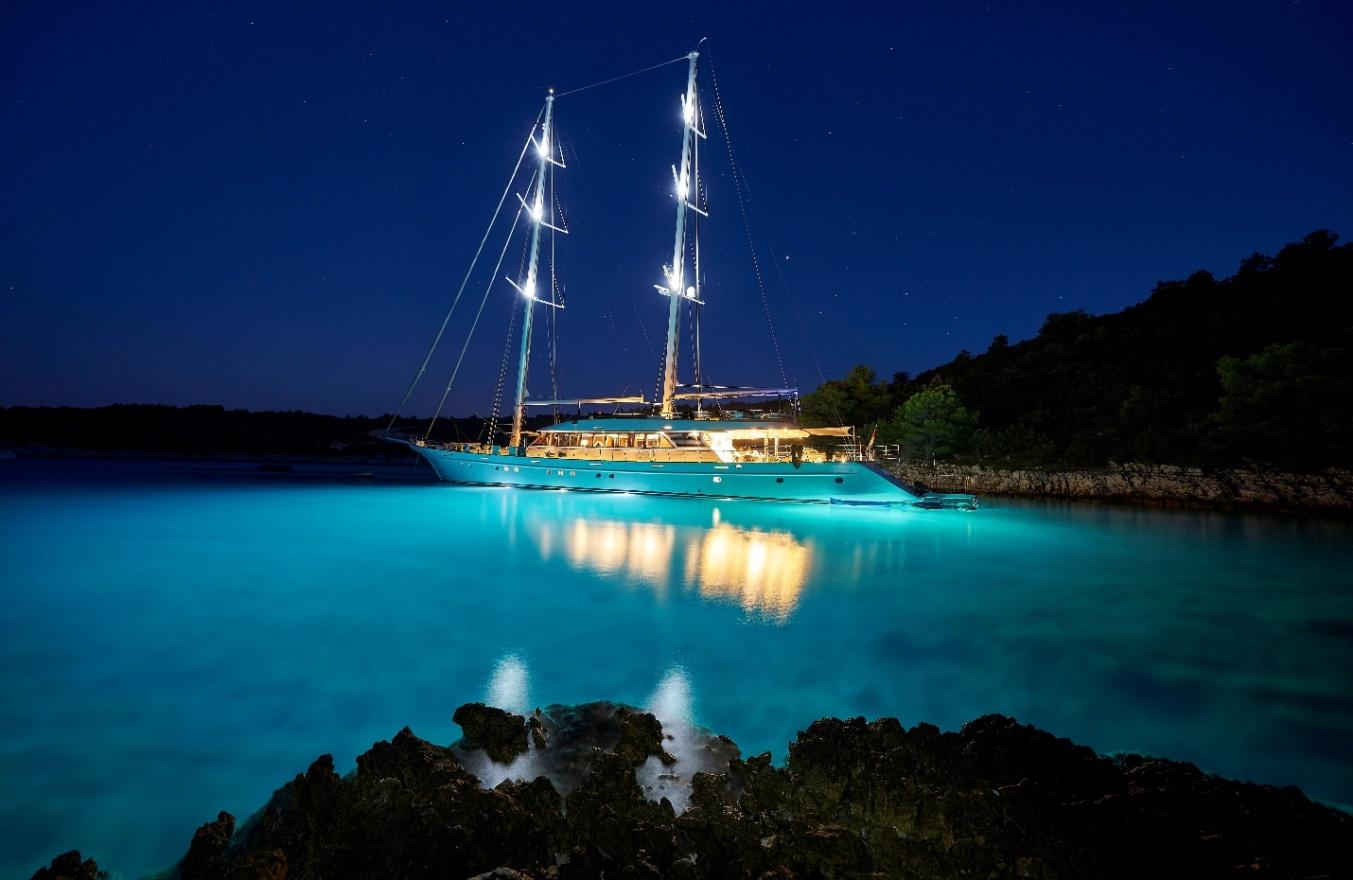 the image of a luxury yacht at evening time with under lights turned on