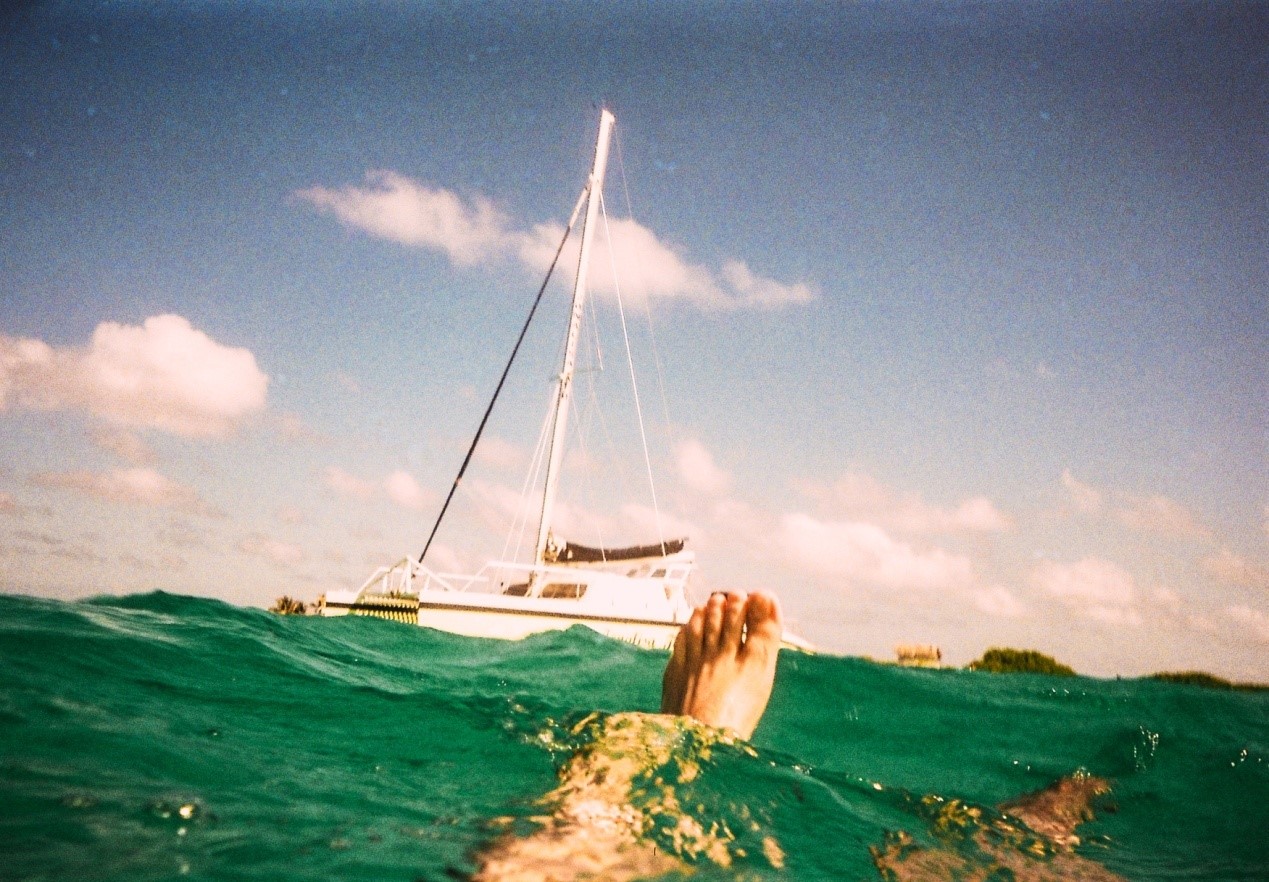 man underwater with white yacht