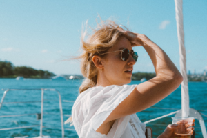a woman wearing shades looking at the horizon while standing in a boat